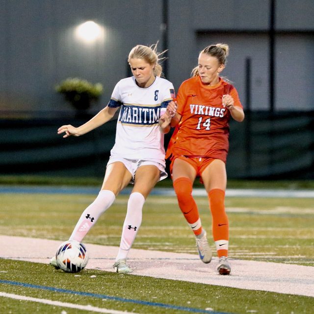 A Buccaneer clearing the ball under pressure from a Salem State forward