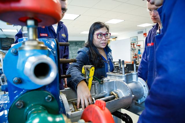 A cadet working on engine equipment in a lab