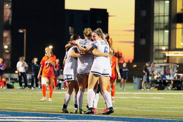 Players celebrating a goal at sunset